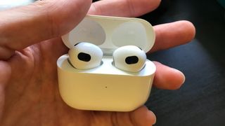 暗い机の横に置かれた Apple AirPods 3
