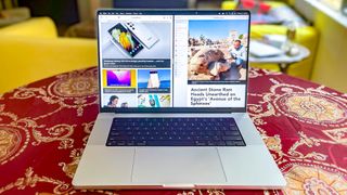 2 つの Web ページを並べて表示しているテーブルに置かれた MacBook Pro 2021 (16 インチ)