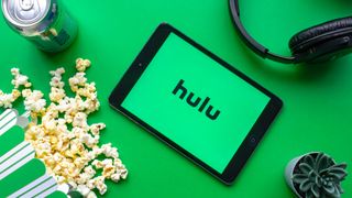 ポップコーン、ソーダ、ヘッドフォン、サボテンに囲まれた Hulu のロゴが入ったタブレット