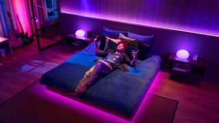 ベッドに横たわり、Philips Hue ライトが音楽に合わせて踊る Spotify を聴いている男性