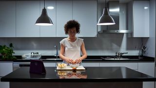 夜に電気をつけてキッチンで食事を準備する女性