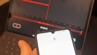 バックグラウンドでラップトップ録音ソフトウェアを備えた携帯電話を持っている手