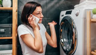 洗濯機の前で電話する女性