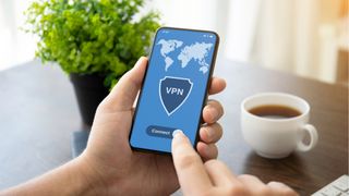 画面に VPN ロゴが表示されたスマートフォンを持っている手