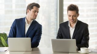 同僚のラップトップ画面からコピーする男性