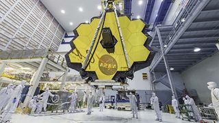 クリーンルームでジェームズ・ウェブ宇宙望遠鏡をクレーンで移動する作業員