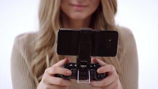 モバイル ゲーム用に電話クリップが付いた Xbox ワイヤレス コントローラーを保持している女性