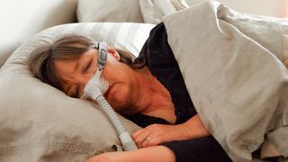 いびきを止めるために横向きに寝ているときにcpapマシンを装着している女性