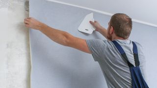 壁に壁紙を掛けている男性