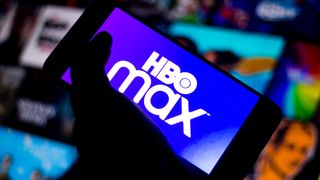 暗闇の中で、他の画面の前で手で持った携帯電話にある HBO Max のロゴ