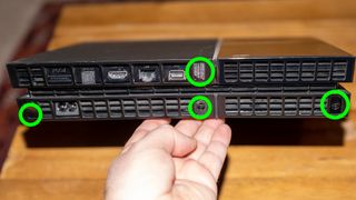 PS4 の背面の写真。取り外す必要があるネジが緑色の円で強調表示されています。