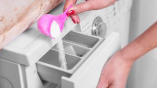 洗濯機のディスペンサーに漂白剤を投入する様子