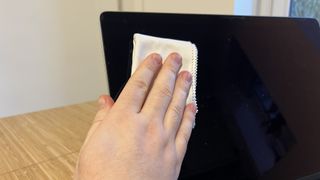 マイクロファイバークロスで拭いているMacBookの画面