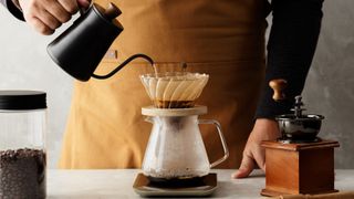 コーヒーに水を注ぐ人。プアオーバーコーヒーの作り方に関する記事を表す