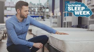 青いシャツと黒いジーンズを着た男性が、購入したいマットレスに手を置く