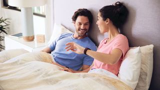 ベッドで女性の手首の睡眠トラッカーを見ているカップル